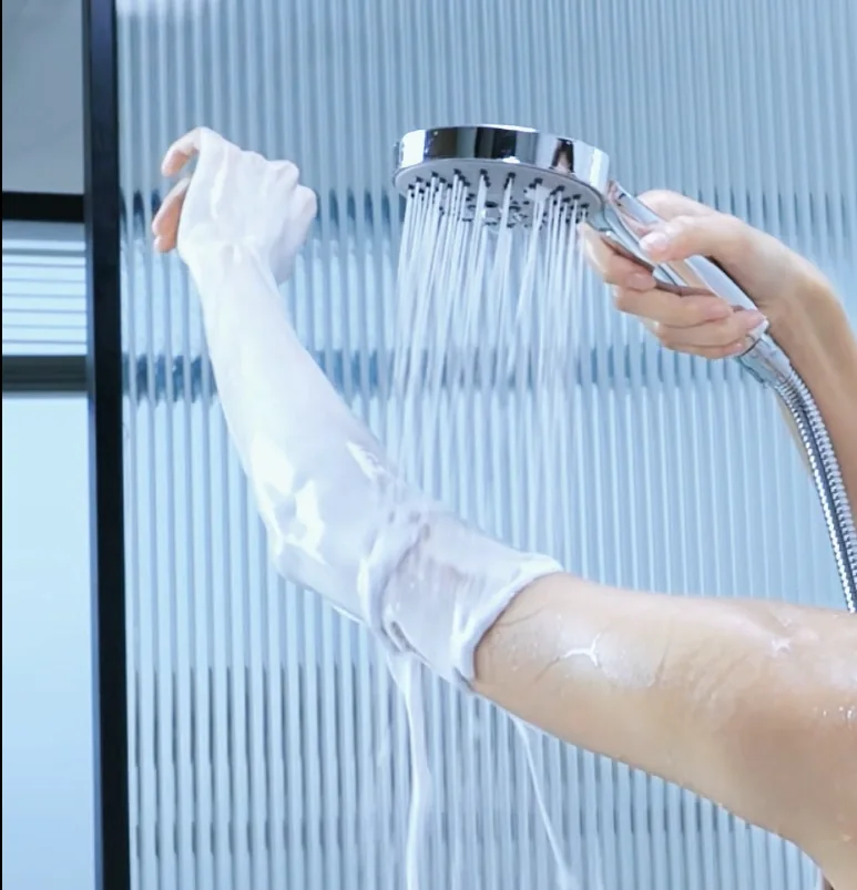 Thick white shower foam on an arm beneath a handheld shower head.